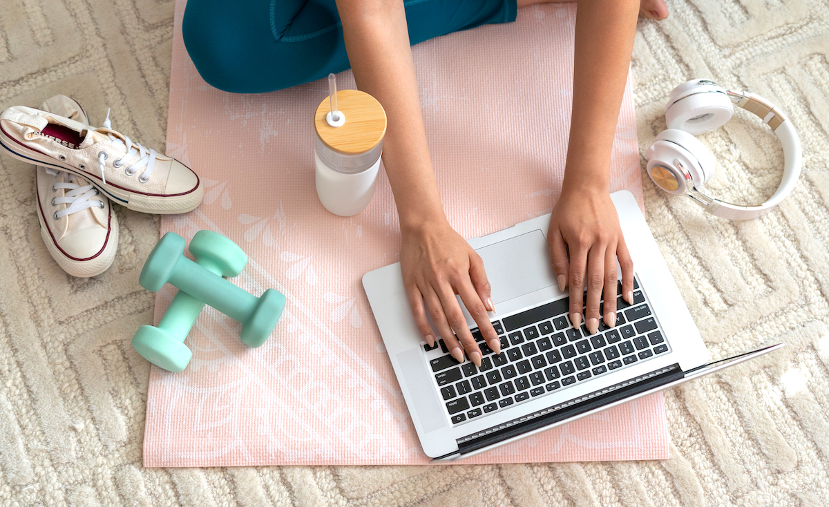 How to find time to exercise as a busy mum woman searching on laptop sitting on yoga mat