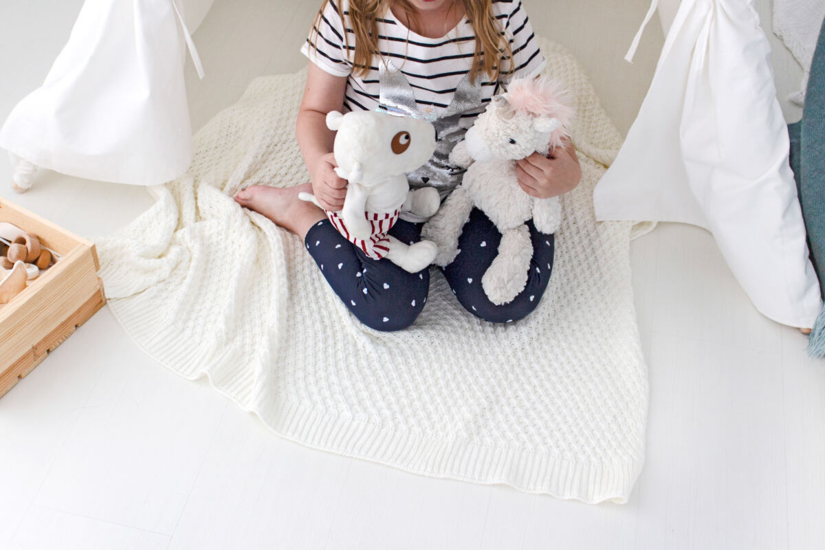 Ways to declutter your kid’s room - child playing with soft toys