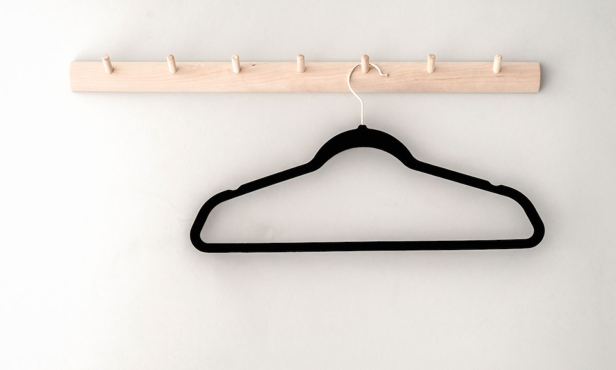 10 tips for organising kids clothes - 1 black hanger hanging on a rack attached to a wall.
