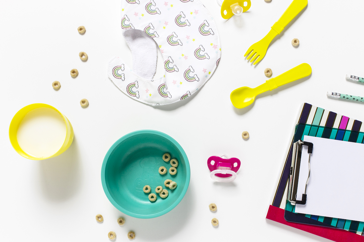 8 tips to create a morning routine for kids - table with cereal, bib, yellow cutlery, and paper.