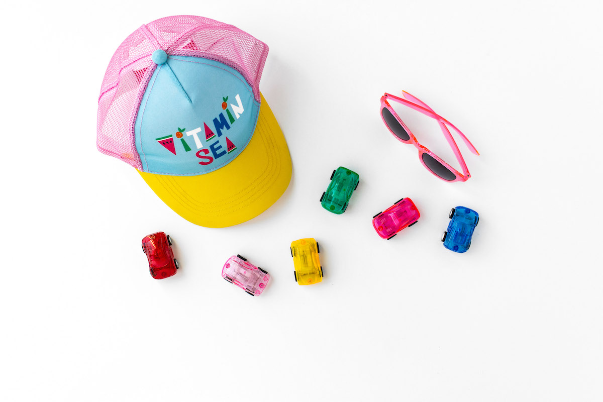 Ultimate guide to keeping your kids engaged all summer - kids hat, cars, and pink sunglasses.