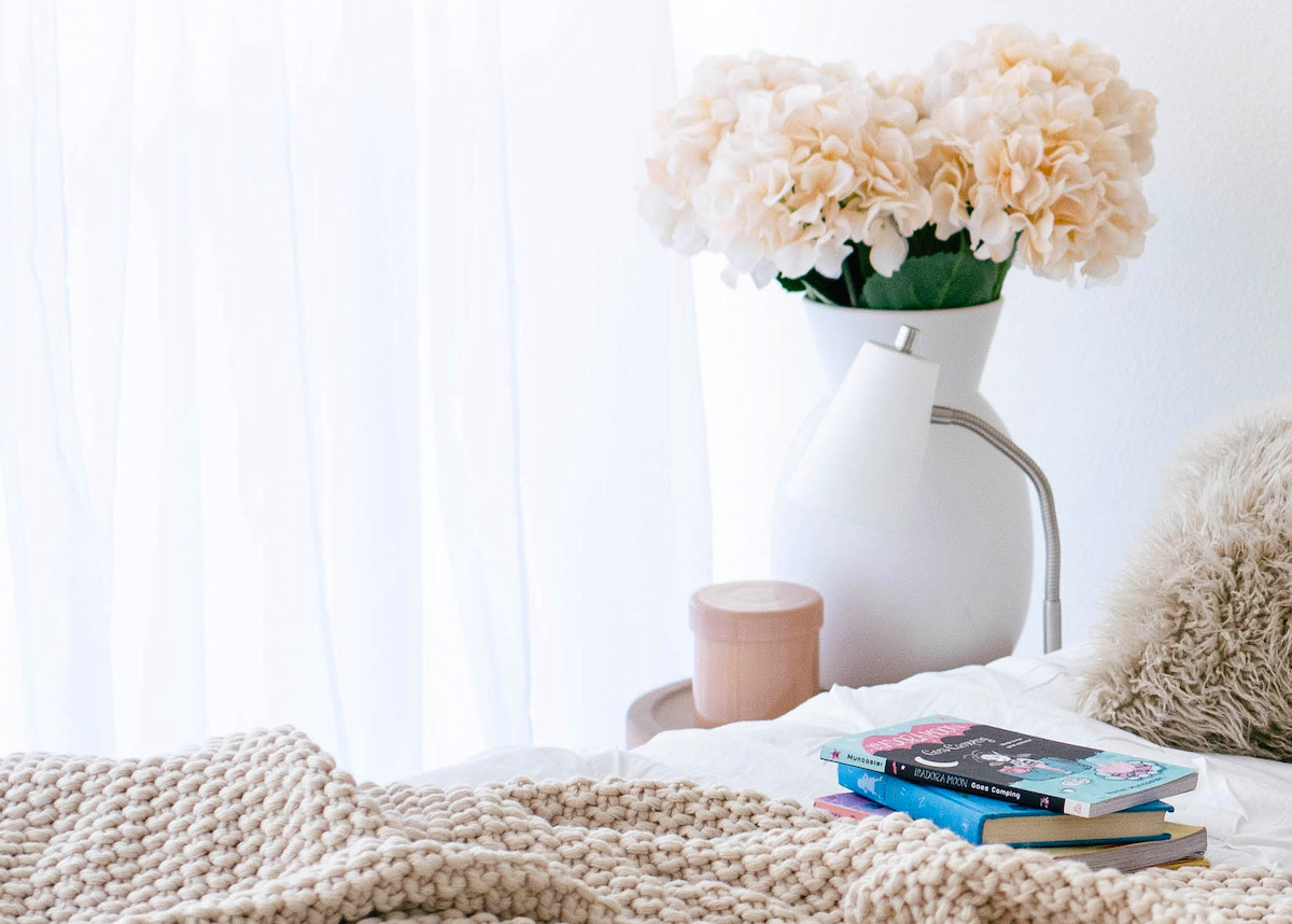 Tips for home upgrades - flowers next to a bed, books on the bed.