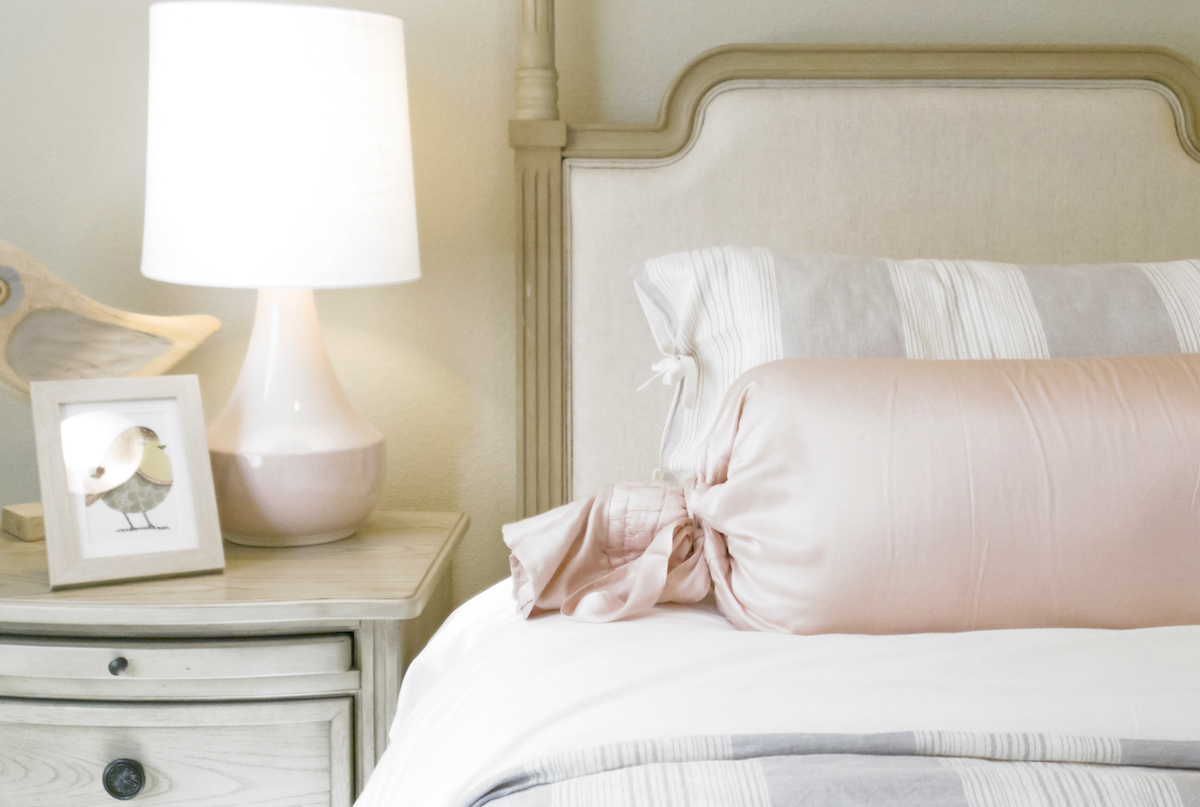 What is home insurance - bed with pink silk pillow and table with lamp.