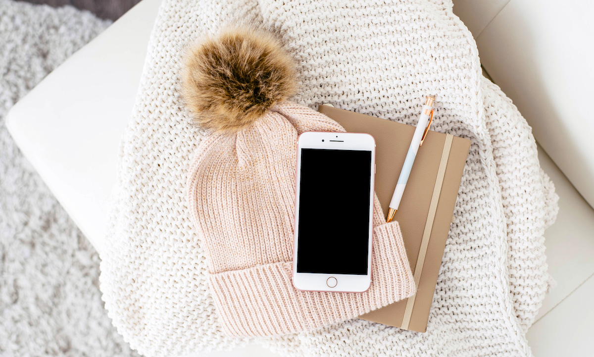 What is home insurance - couch, beanie, notebook and phone.