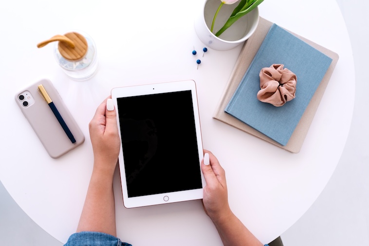 woman holding a tablet, with a phone, tulip, and water bottle - one of the things you can do in 20 minutes.