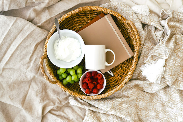 Bed with cereal, mug, fruit, and 2 notebooks - a great way to create morning routines for mums.