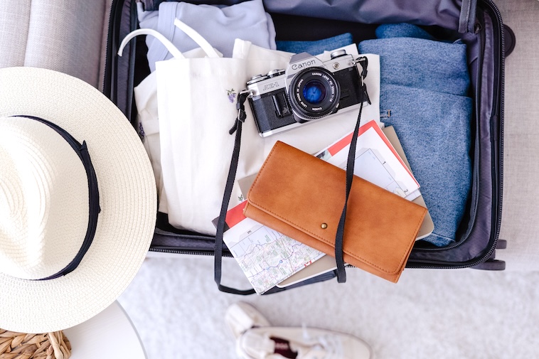 Suitcase with clothes, camera and travel documents - one of the ways to plan for a European road trip.