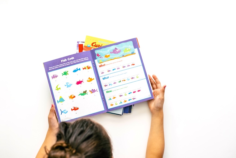 Girl reading an educational book - one of the things you can buy to prepare for school holidays.