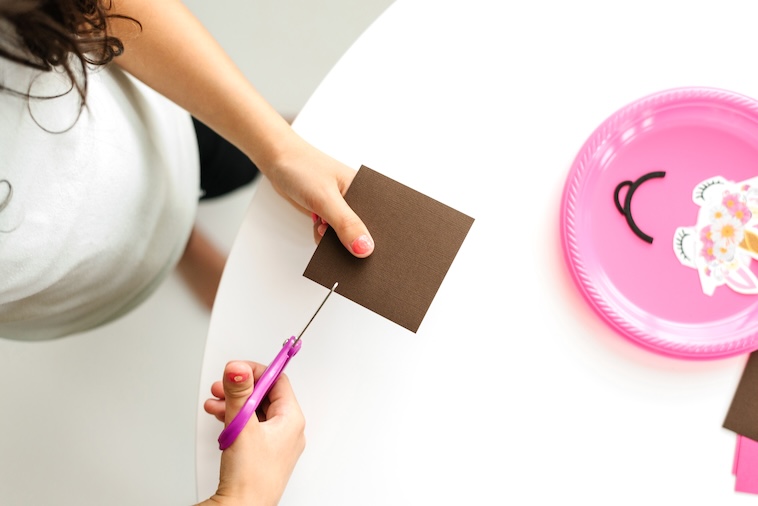 Girl cutting a piece of paper - something you can practice to prepare for the first day of school.