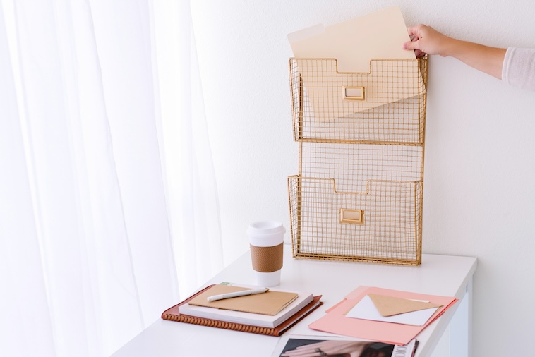 Woman placing a folder in a paper holder with coffee and notebooks in front of her - things you need to prepare for back to school.