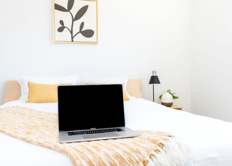 Bedroom with bed, yellow cushion, floral print, bedside table, lamp - updating bedrooms is one of the home improvement ideas you can try.