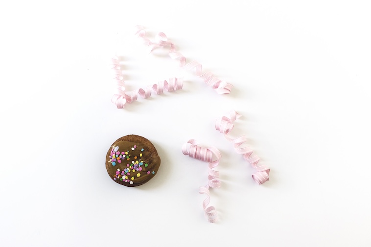 Chocolate cup cake with sprinkles next to pink ribbon - organising food is one of the top event planning time saving tips.