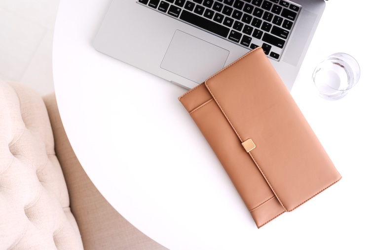 Coffee table, laptop, wallet, glass of water, pink couch - some supplies you need to become an organised mum.