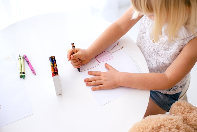 Girl drawing with crayons - an activity if you're looking for how to improve children's concentration and focus.