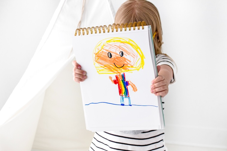 Girl holding a drawing of a person - an activity if you're looking for how to improve children's concentration and focus.