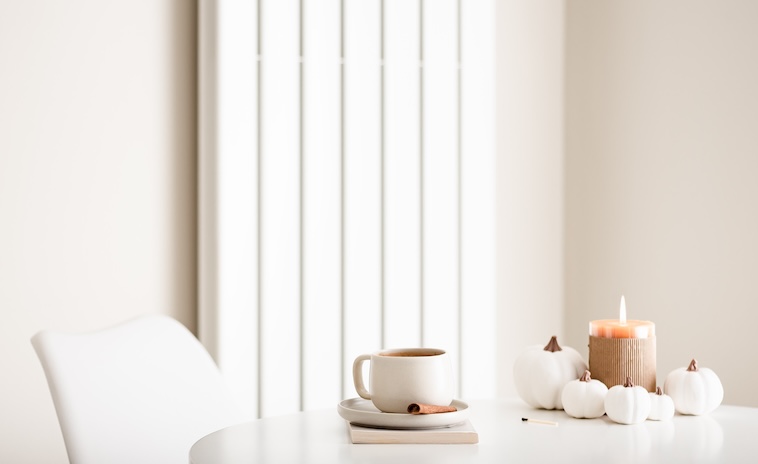 Coffee table with 3 ceramic pumpkins on it, a candle, and coffee cup - decorating a home is a great home improvement idea.