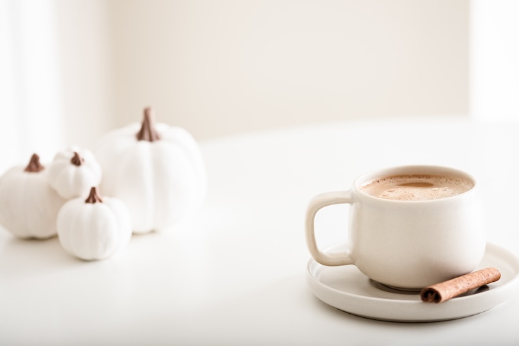 Coffee table with 3 ceramic pumpkins on it, a candle, and coffee cup - decorating a home is a great home improvement idea.