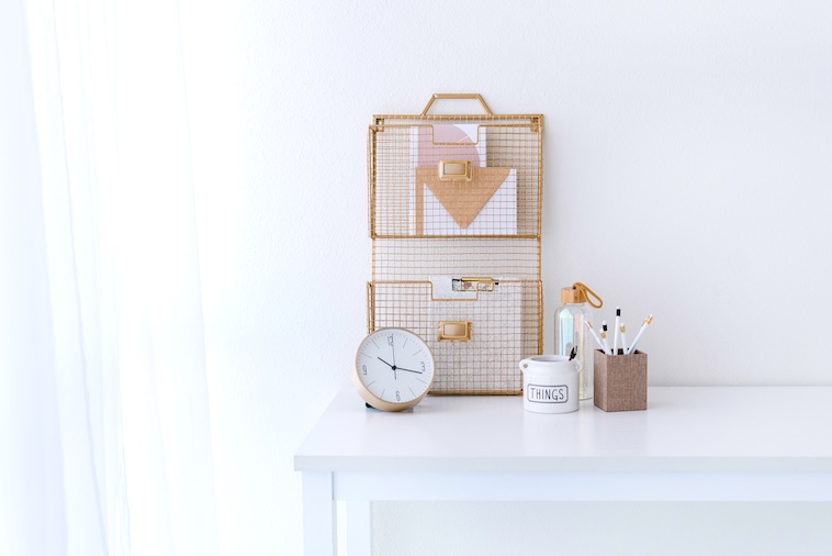 Desk with mug, clock, notebook, baskets and stationery holder - things you need when using time blocking.