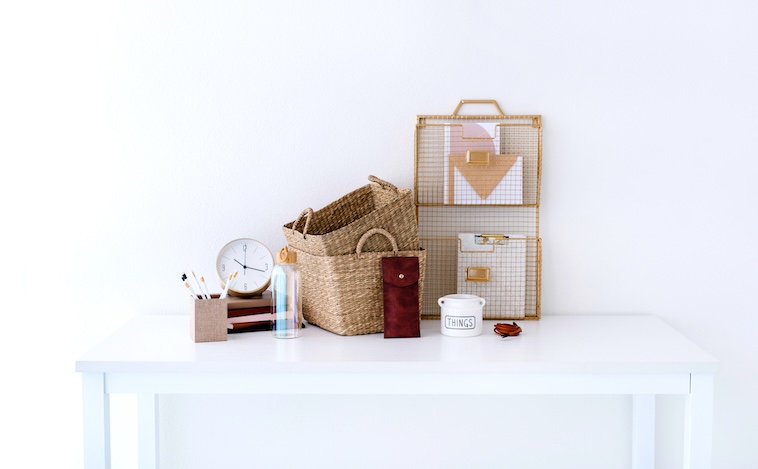 Desk with water bottle, clock, notebook, baskets and stationery holder - things you need when using time blocking.