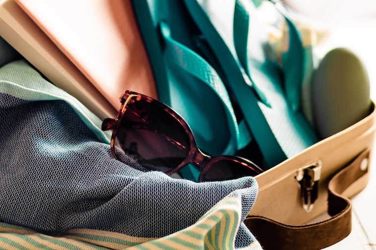 Bag with notebooks, flip flops, sunglasses - things to remember when doing beach vacation prep.