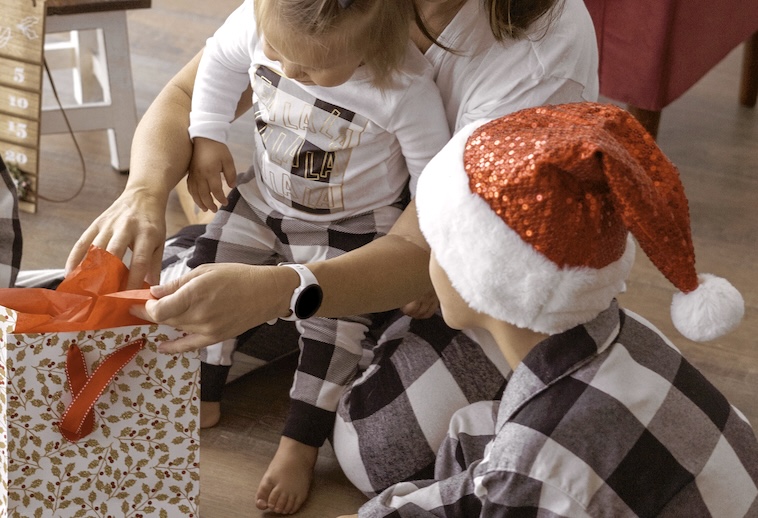 Mum with little girl and boy getting Christmas present from bag - things to do to prepare for Christmas early.