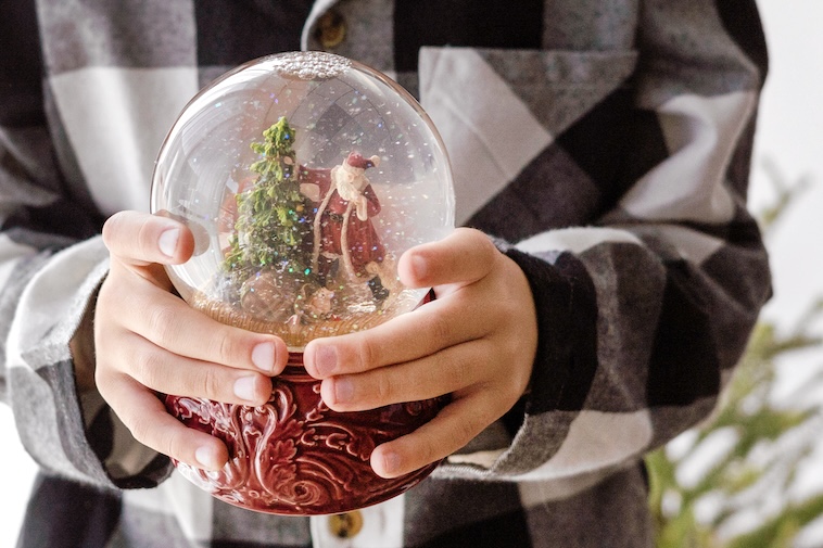 Boy holding Christmas snow globe - things to do to prepare for Christmas early.