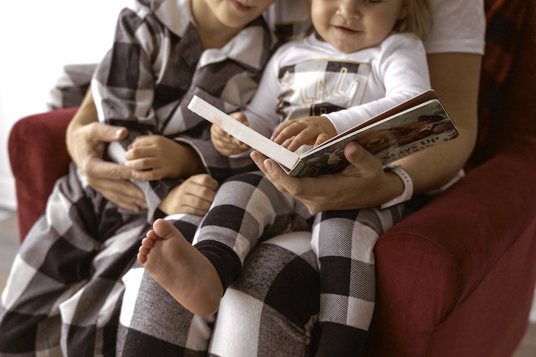 Mum reading a Christmas book to 2 young kids - things to do to prepare for Christmas early.