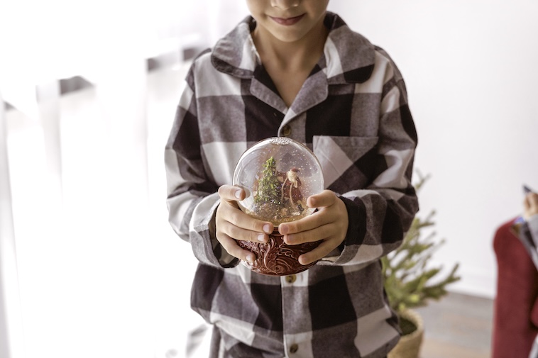 Boy holding Christmas snow globe - things to do to prepare for Christmas early.