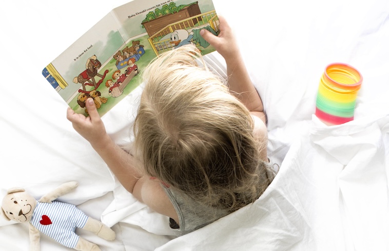 Girl reading in bed - relaxing is a nasal care tips for kids.