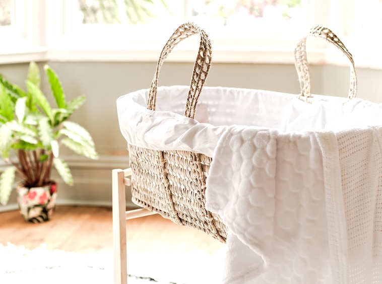 Baby moses basket with blanket hanging out - a guide to baby essentials.