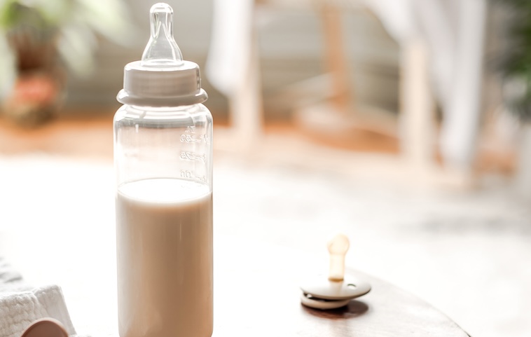 Baby bottle with milk, dummy on table - feeding babies is one of the parenting worries to let go off.