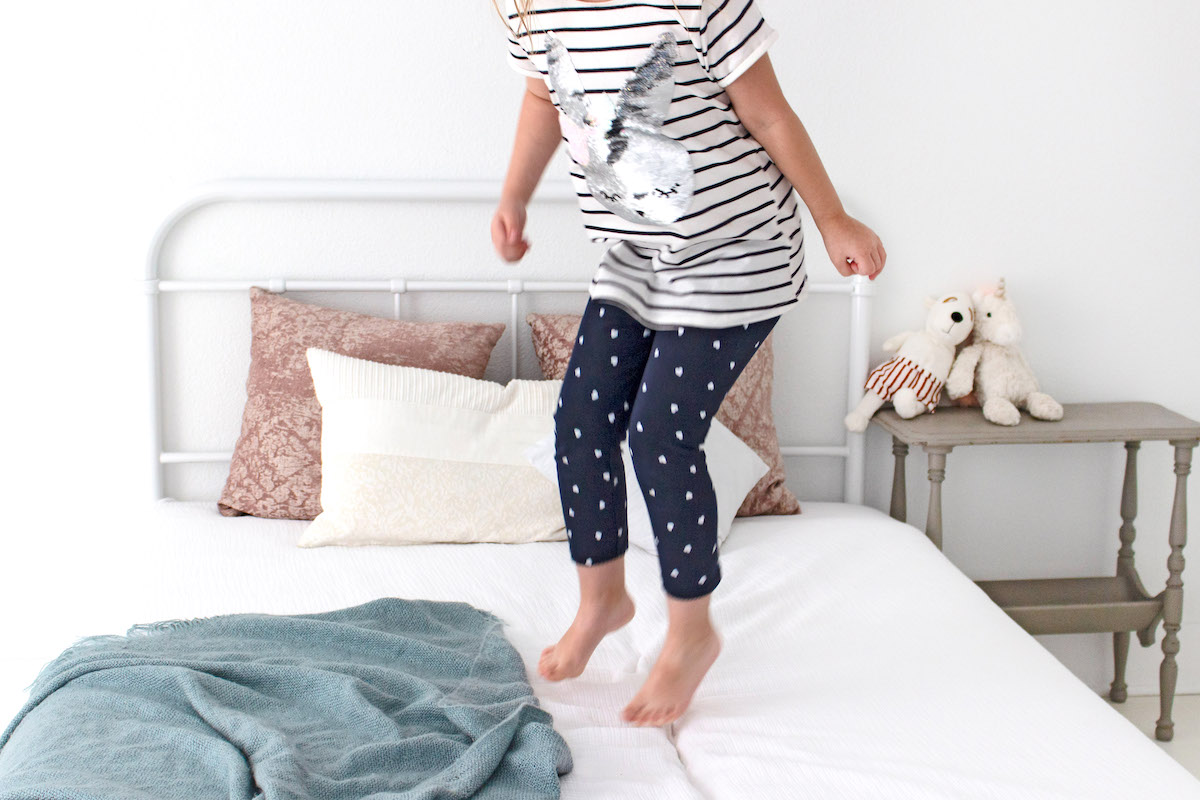 What is mum guilt and how to overcome it - girl jumping on bed.