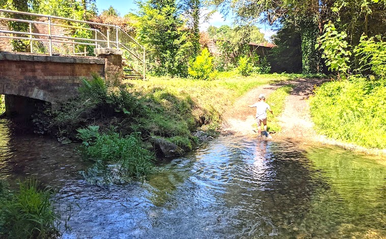 Boy walking through a creek - a fun addition to a summer family bucket list.
