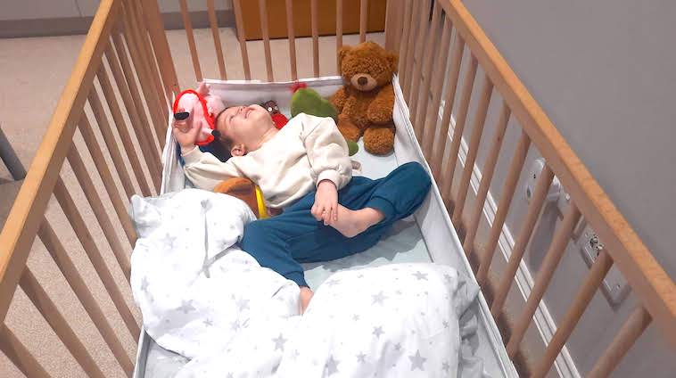 Boy in cot with toys and toddler bedding - part of a series of tips on when to use a duvet for your toddler.