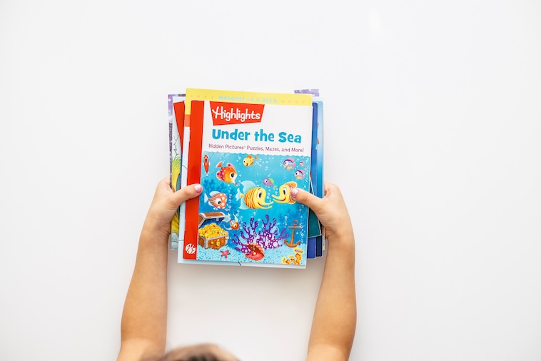 Young child holding educational books - some of the preschool activities you can try.