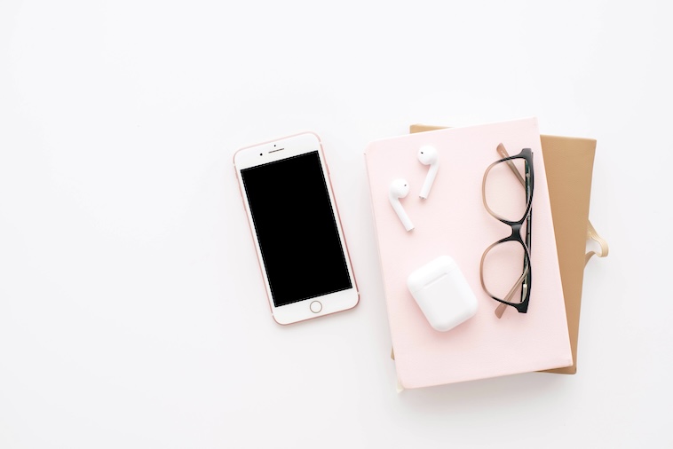 Phone, notebooks, glasses, ear buds and ear bud case - things you need when using a bullet journal and Google Calendar together.