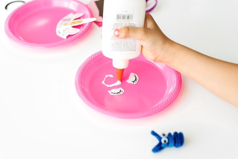 Child gluing eyes onto a pink paper plate - things you can do at home to prepare for the first day of school.