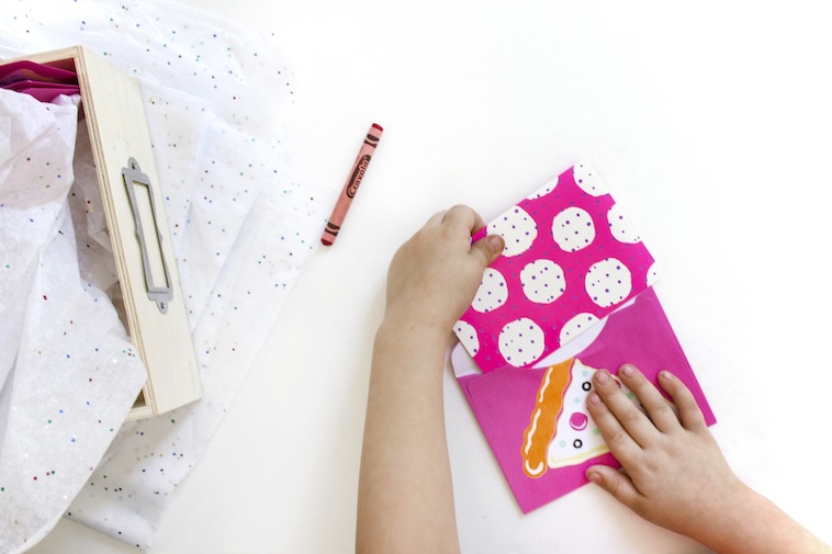 Child putting a pink invitation into an envelope - sending invitations early is one of the top event planning time saving tips.