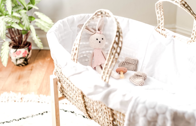 Moses basket with a bunny and dummy - comforting things you can use as ways to reduce a baby’s fever.