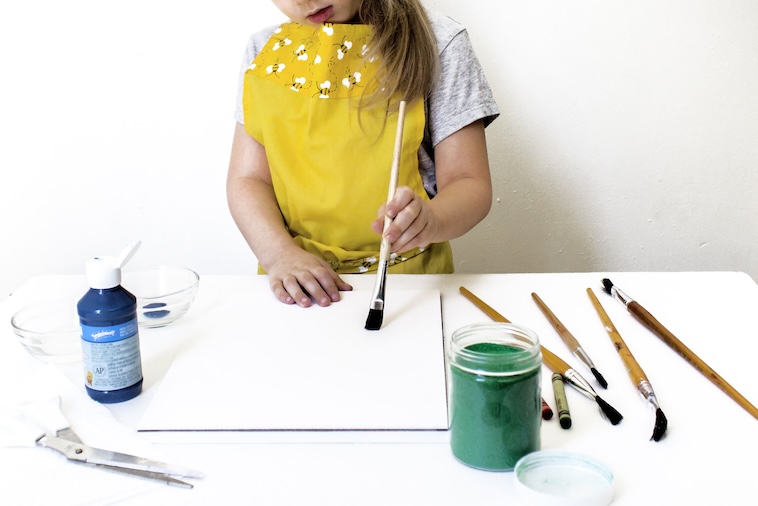 Girl painting on plain paper with art supplies - one of the ways to prepare your child for kindergarten.